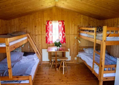 Fembäddsstuga med våningssängar och matbord på Valle Camping nära Skara Sommarland
