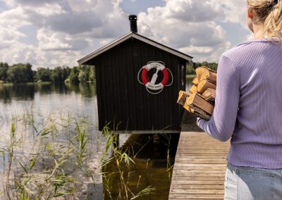 Person bär ved till bastun vid sjön på Valle Camping